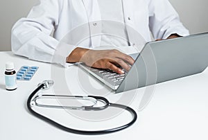 Hands of an afro female doctor using a laptop photo