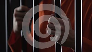 Hands of angry arrested male gripping prison bars, unfair judgment, closeup