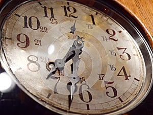 Hands of antique mechanical wall clock behind glass