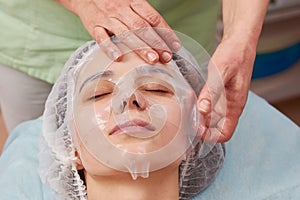 Hands applying collagen facial mask.