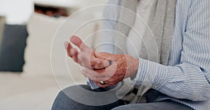 Hands, arthritis or carpal tunnel with a senior person on a sofa in the living room of a retirement home closeup. Wrist