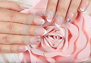 Hands with artificial french manicured nails and pink rose flower