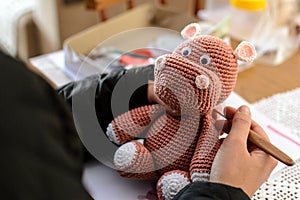 Hands of an artisan creating a plush hippo using the amigurumi crochet technique