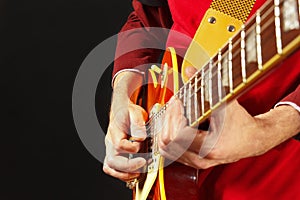 Hands of artist playing the electric guitar on dark background