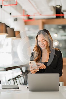 Hands of Asian businesswoman using smartphone and mobile calculator Work on a laptop computer with a calculator on the table with