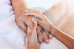 Hands of asian child girl holding elderly grandparent hands wrinkled skin