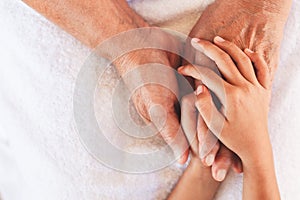 Hands of asian child girl holding elderly grandparent hands wrinkled skin