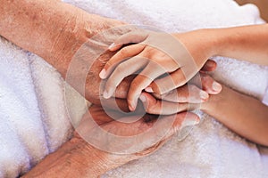 Hands of asian child girl holding elderly grandparent hands wrinkled skin