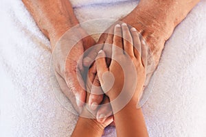 Hands of asian child girl holding elderly grandparent hands wrinkled skin