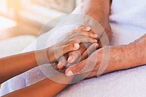 Hands of asian child girl holding elderly grandparent hands wrinkled skin