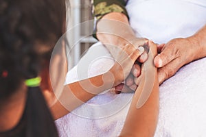 Hands of asian child girl holding elderly grandparent hands wrinkled skin