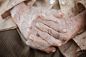 Hands Asian elderly woman grasps her hand on lap, pair of elderly wrinkled hands in prayer sitting alone in his house, World Kind