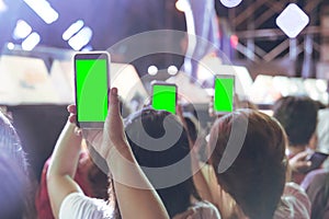 Hands of audience crowd people taking photo with mobile smart phone with green screen in party concert