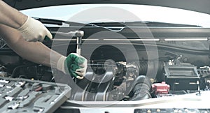 Hands of an auto mechanic with a socket wrench in the engine compartment of a car during repairs
