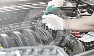 Hands of an auto mechanic with a socket wrench in the engine compartment of a car during repairs