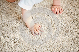 Hands of baby crawling on floor or carpet
