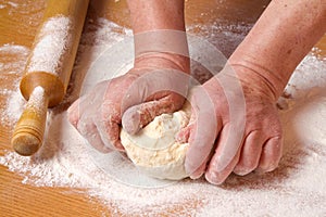 Hands of the baker knead a piece dough