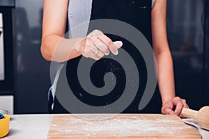 Hands of baker woman female making sprinkling flour dough