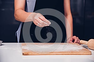 Hands of baker woman female making sprinkling flour dough