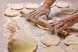 Hands baking dough with rolling pin on wooden table. Old woman hands hands keep rolling pin with flour on table, baking