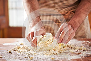 Hands baking dough on wooden table