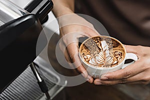 Hands of barista holding a cup of Latte coffee