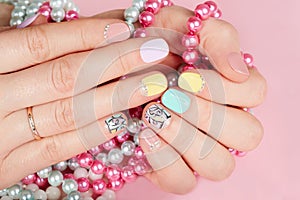 Hands with beautiful manicured nails holding colorful necklaces