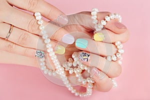 Hands with beautiful manicured nails holding pearl necklace