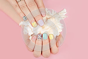 Hands with beautiful manicured nails and sea shell