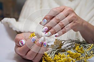 hands with a beautiful multi-colored manicure hold a bouquet of yellow flowers