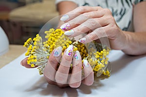 hands with a beautiful multi-colored manicure hold a bouquet of yellow flowers