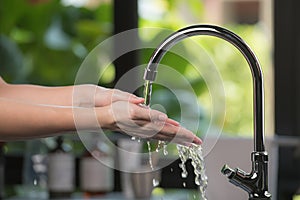 Hands being washed scrubbed and rinsed using disinfectant soap for hygiene and protection against COVID-19 and other dieseases