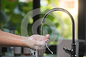 Hands being washed scrubbed and rinsed using disinfectant soap for hygiene and protection against COVID-19 and other dieseases