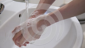 Hands being washed thoroughly with soap under running water for at least 20 seconds and then rinsed in order to fight Corona