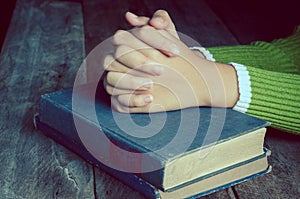 Hands with Bible on wood table.