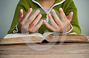 Hands with Bible on wood table.