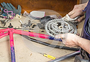 Hands of bicycle mechanic cleaning chainring bike