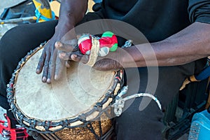 Hands of a black man playing a traditional drum.