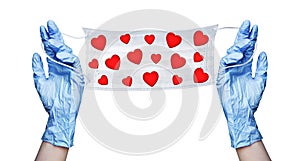 Hands in blue gloves hold medical face mask with red hearts pattern, coronavirus protection on Valentines Day concept love, safety