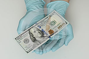 Hands in blue latex gloves hold dollars banknotes on white background. Money, earnings, crediting and finance