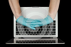 Hands in blue protective gloves typing on laptop keyboard. Top view. Coronavirus concept
