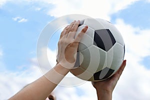 Hands, blue sky and closeup of ball for soccer exercise, game or training in outdoor field. Sports, fitness and zoom of