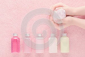 Hands with a bottle and natural cosmetic bottles, shampoo, lotion, shower gel and other products, above