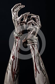 Hands bound,bloody hands, mud, rope, on a black background, isolated, kidnapping, zombie, demon