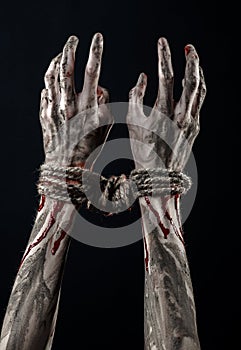 Hands bound,bloody hands, mud, rope, on a black background, isolated, kidnapping, zombie, demon