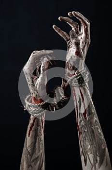 Hands bound,bloody hands, mud, rope, on a black background, isolated, kidnapping, zombie, demon