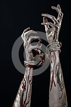 Hands bound,bloody hands, mud, rope, on a black background, isolated, kidnapping, zombie, demon