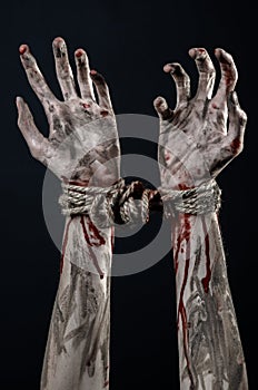 Hands bound,bloody hands, mud, rope, on a black background, isolated, kidnapping, zombie, demon