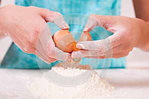 Hands breaking egg into flour