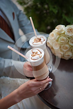 Hands of bride and groom. Cappuccino or latte coffee with heart